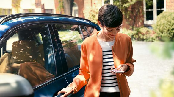 BMW Paket Care Frau mit Smartphone an der Tür ihres BMW